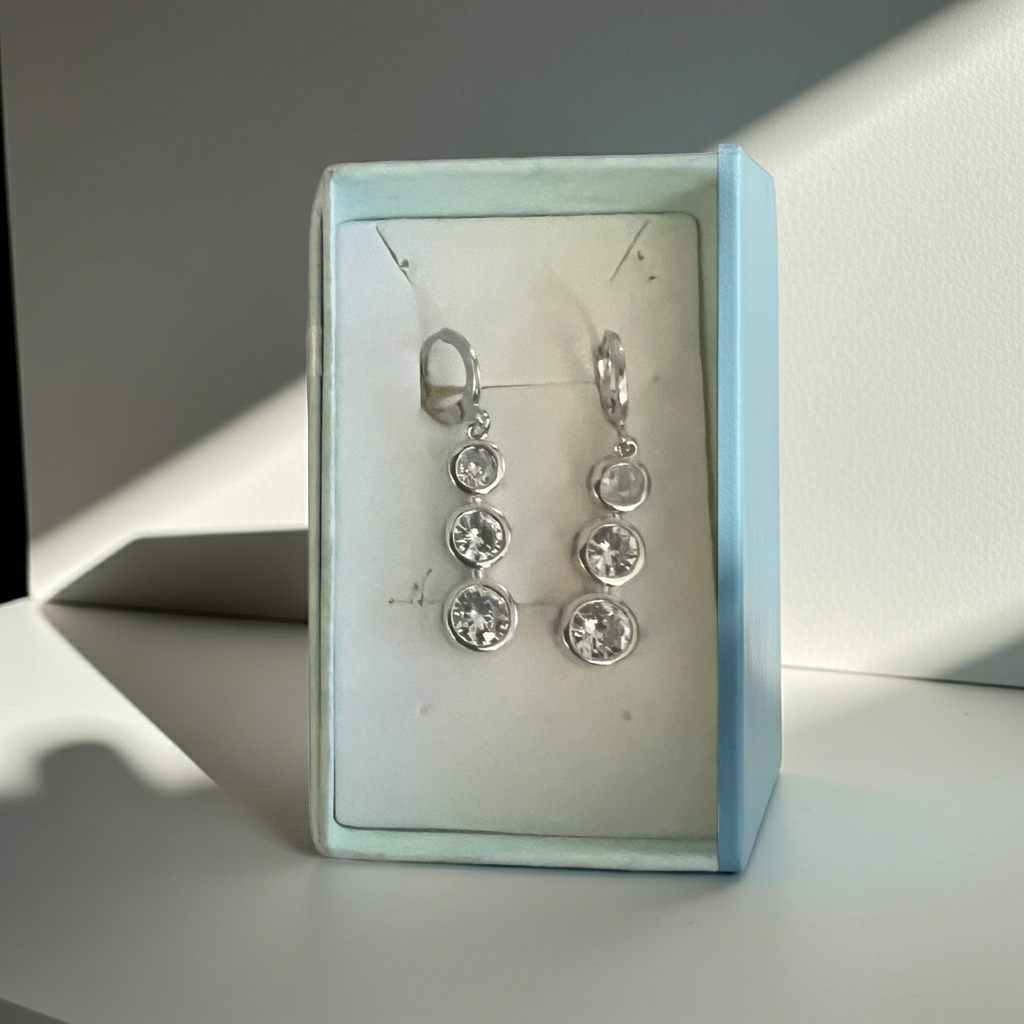 Three-stone bezel-set rhinestone drop earrings in silver-tone with leverback closure, close-up view