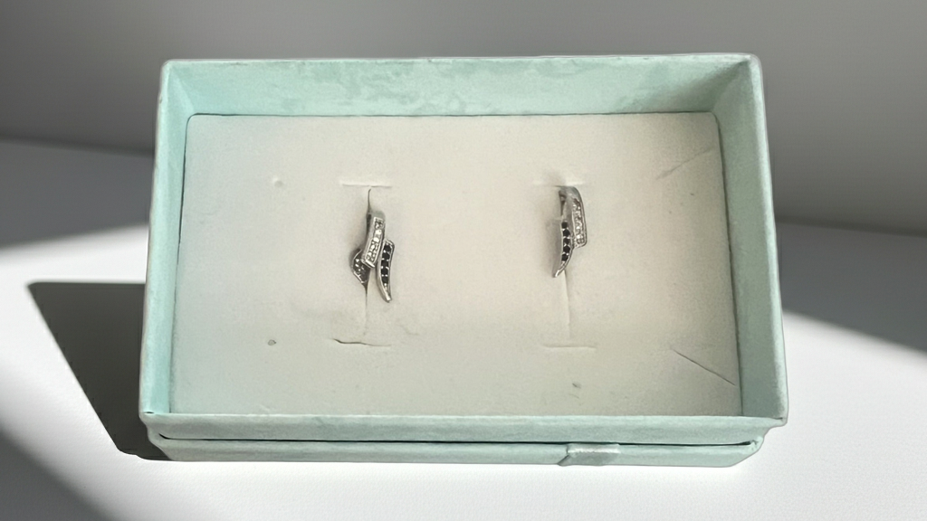 Silver-tone curved wave stud earrings set with alternating clear and black rhinestones, detail view