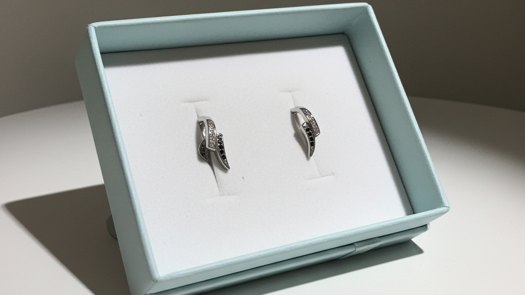 Silver-tone curved wave stud earrings set with alternating clear and black rhinestones